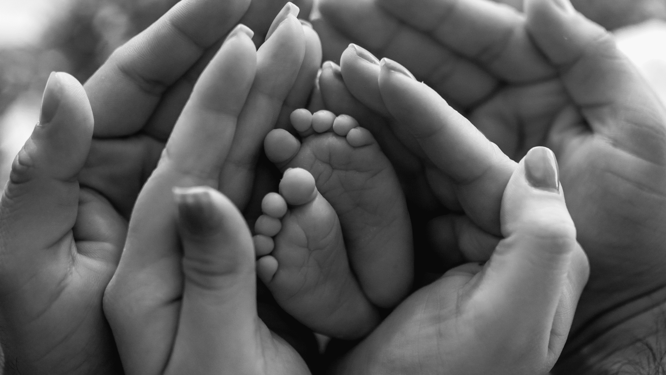Family hands holding baby feet in them